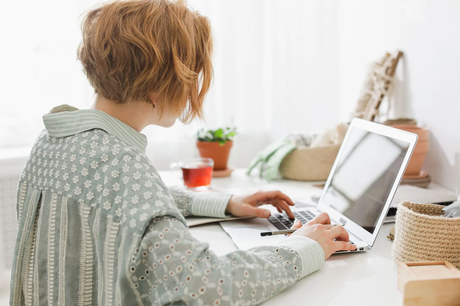 Personne assise à un bureau, de dos, saisissant des informations sur un ordinateur portable