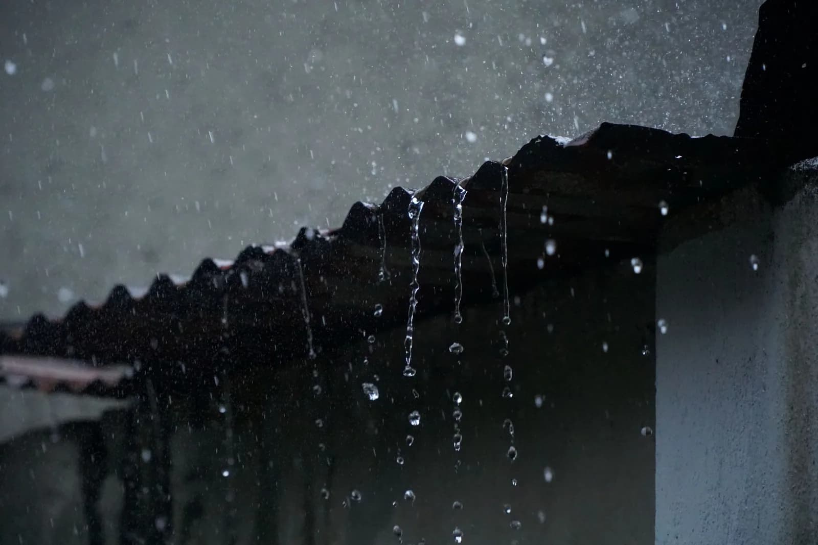 Eau de pluie qui ruisselle sur un toit de tôle ondulée sous une forte averse