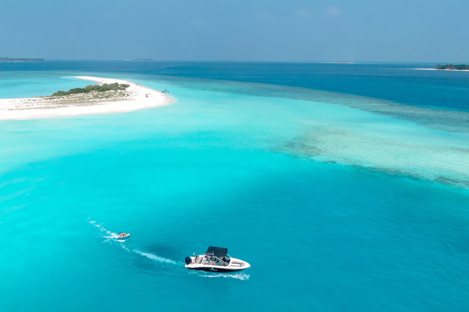 Petit bateau à moteur sur une eau turquoise près d'un banc de sable