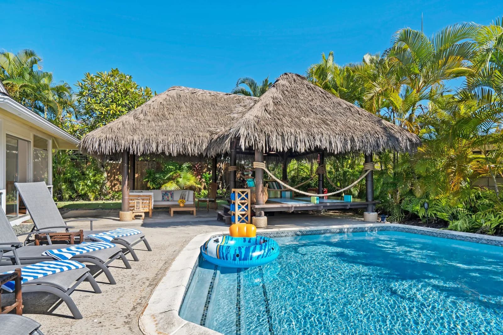 Piscine d'une résidence tropicale avec paillote, transats et végétation