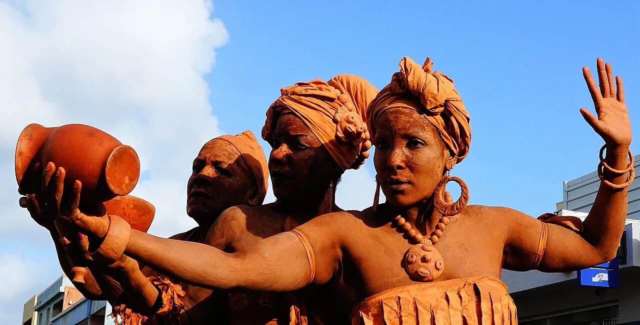 Trois personnes au corps recouvert d'argile, en posture figée, lors du carnaval de Martinique
