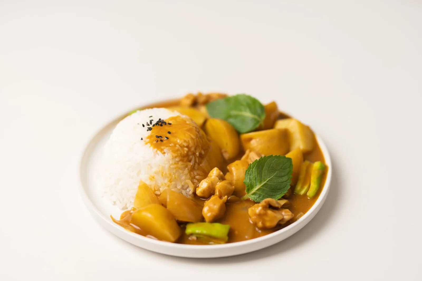 Assiette de curry jaune de poulet et pommes de terre avec un dôme de riz blanc