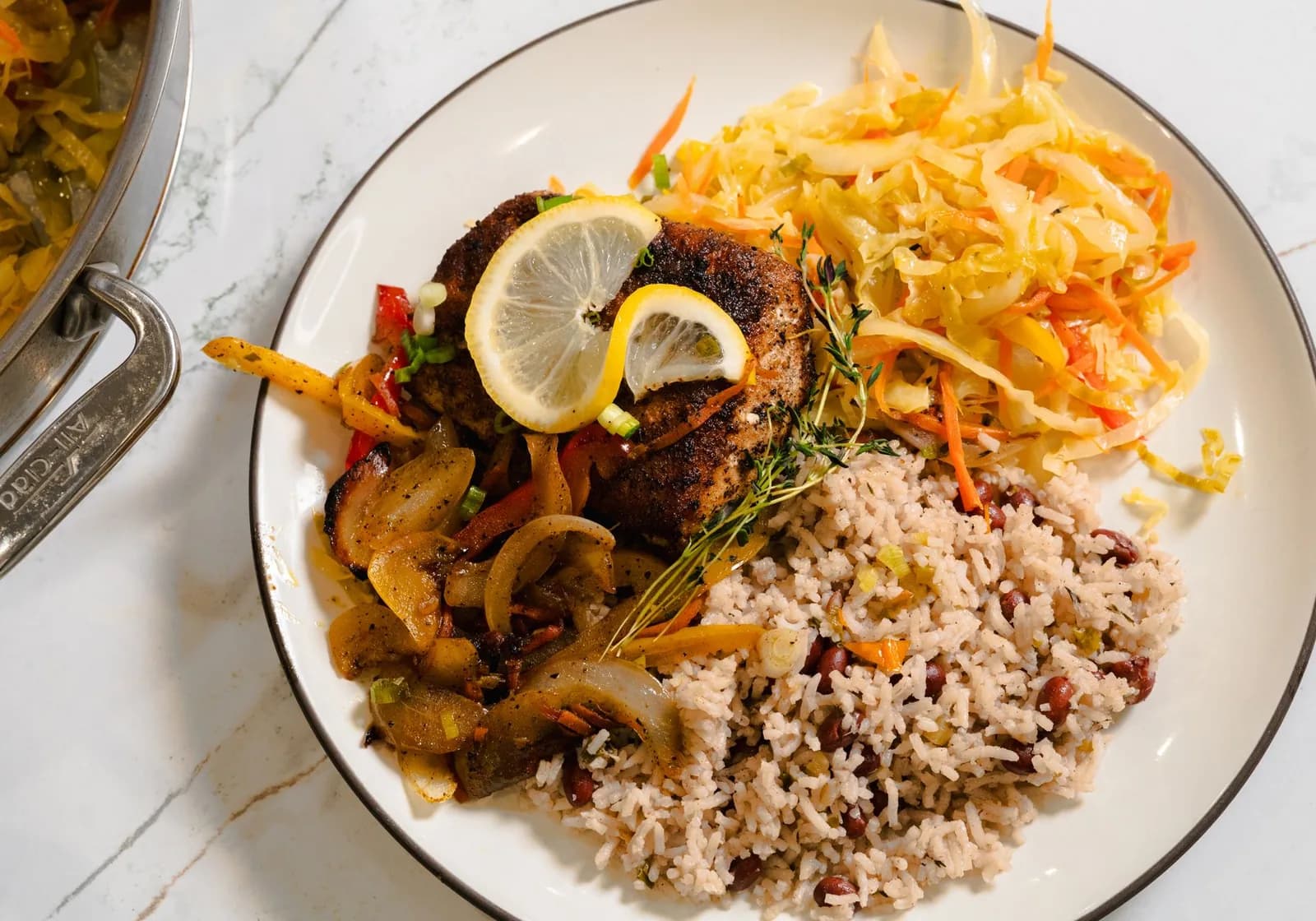 Assiette de poisson épicé avec riz aux haricots, salade de chou et rondelles de citron
