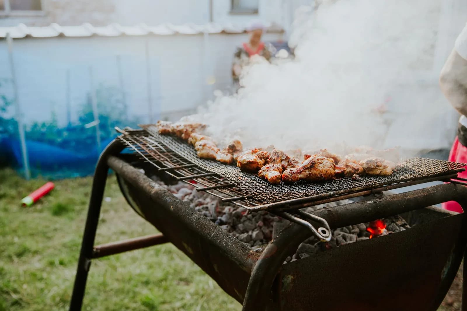 Morceaux de poulet grillés sur un barbecue au charbon en plein air, dans la fumée