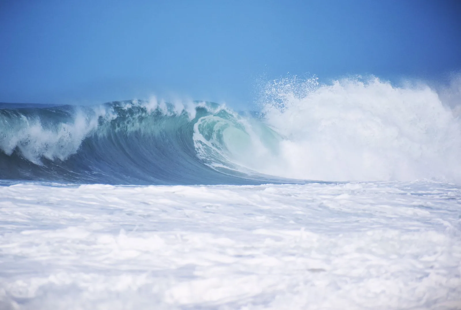 Grosse vague qui déferle dans une mer agitée, couverte d'écume