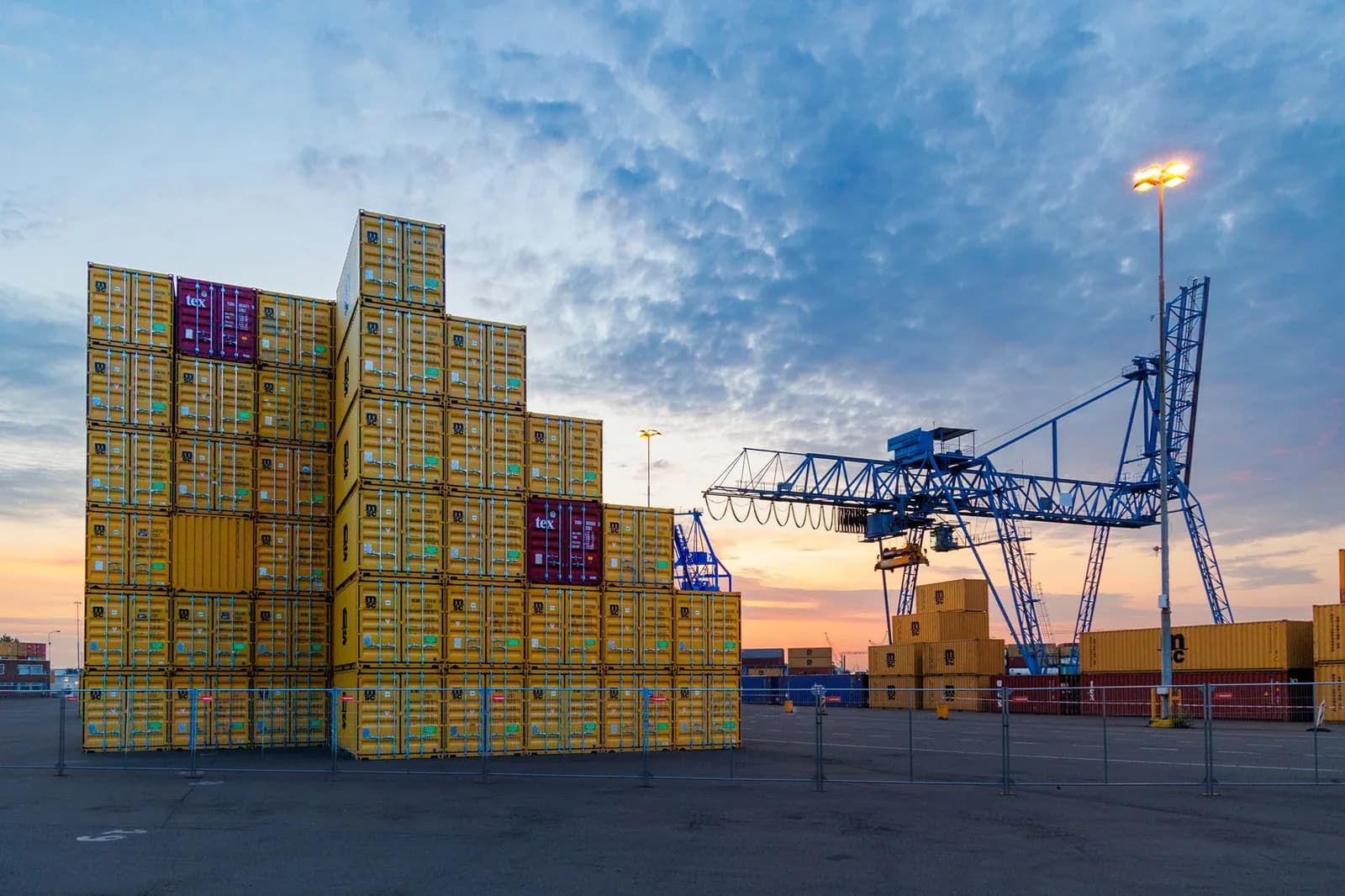 Conteneurs maritimes empilés sur un quai de port, avec une grue portique