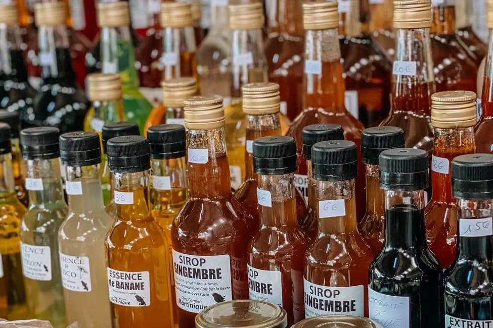 Étal de sirops et d'essences (gingembre, banane, coco) sur un marché de Martinique