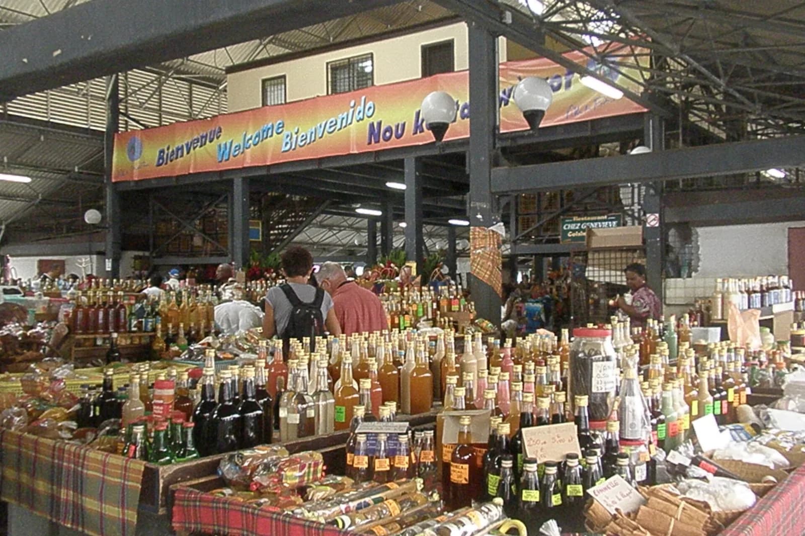 Étals de rhums arrangés, bouteilles et épices sous la halle du Grand Marché de Fort-de-France