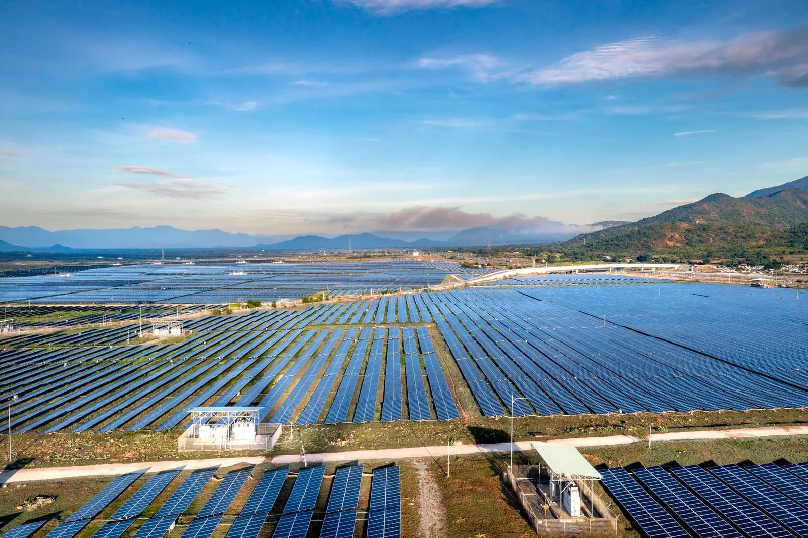 Centrale photovoltaïque vue du ciel, panneaux solaires alignés au pied de collines