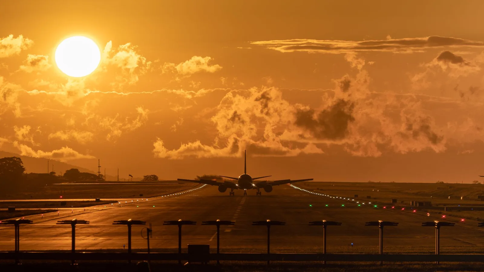 Avion en bout de piste au coucher du soleil, ciel orangé