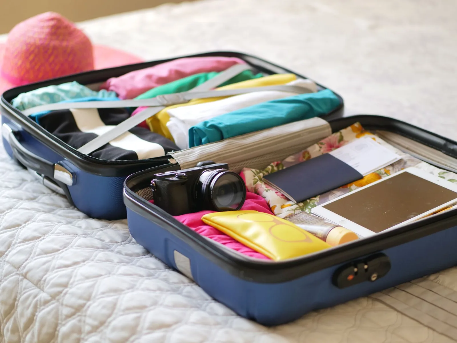 Valise ouverte avec un passeport, un billet, un appareil photo et des vêtements d'été pour préparer un voyage