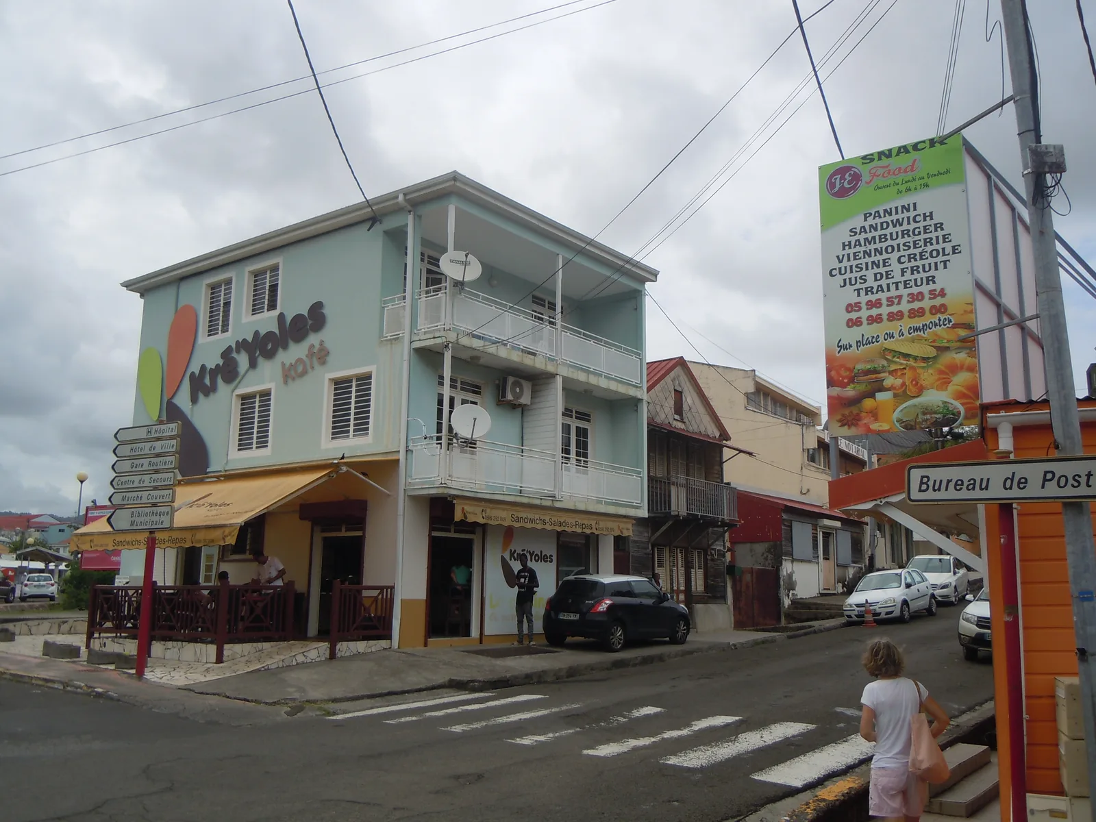 Carrefour commerçant du centre-ville du François, en Martinique, avec snack, immeuble à balcons et panneaux de direction