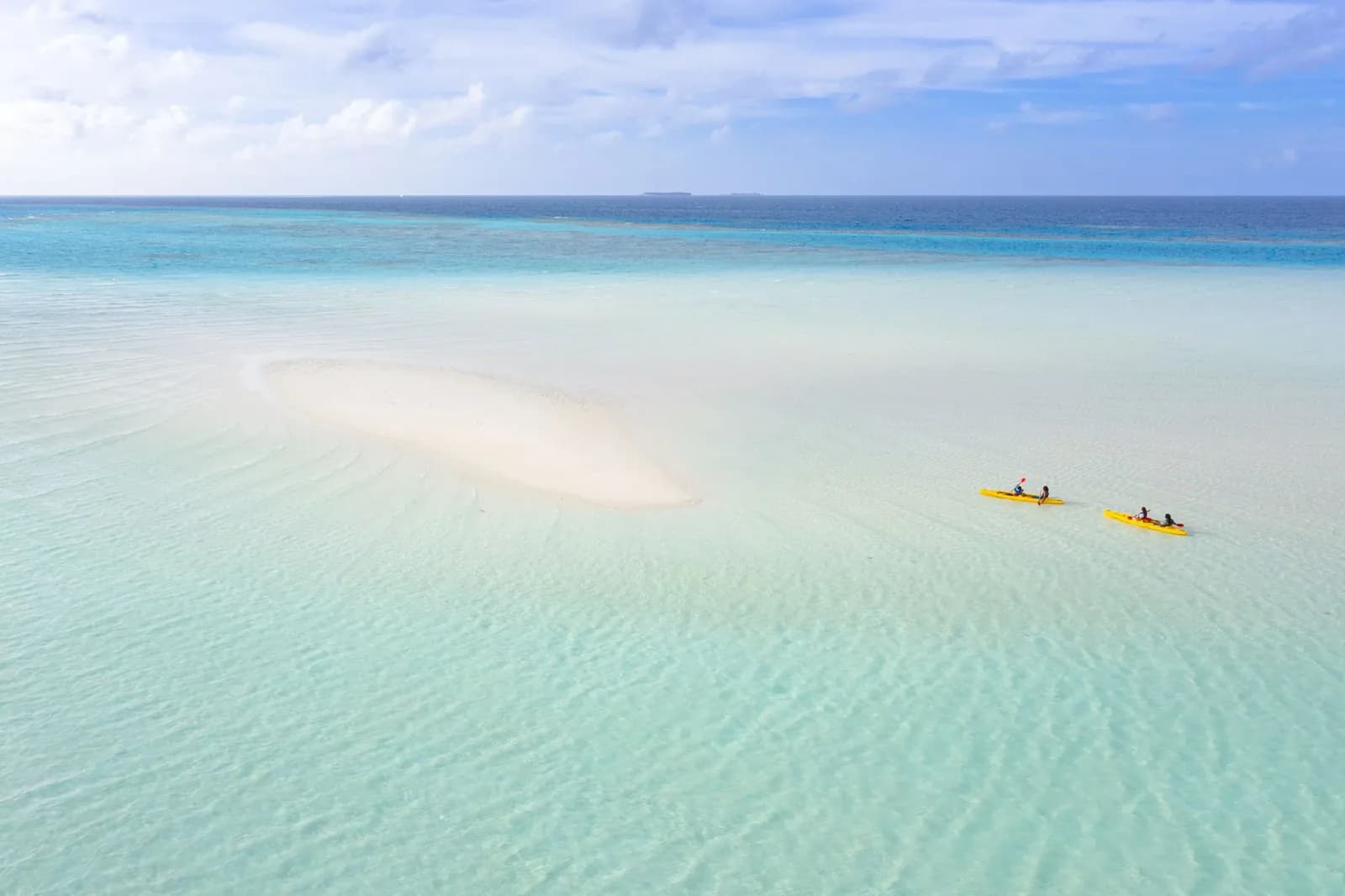 Vue aérienne de deux kayaks jaunes sur une eau turquoise peu profonde près d'un banc de sable