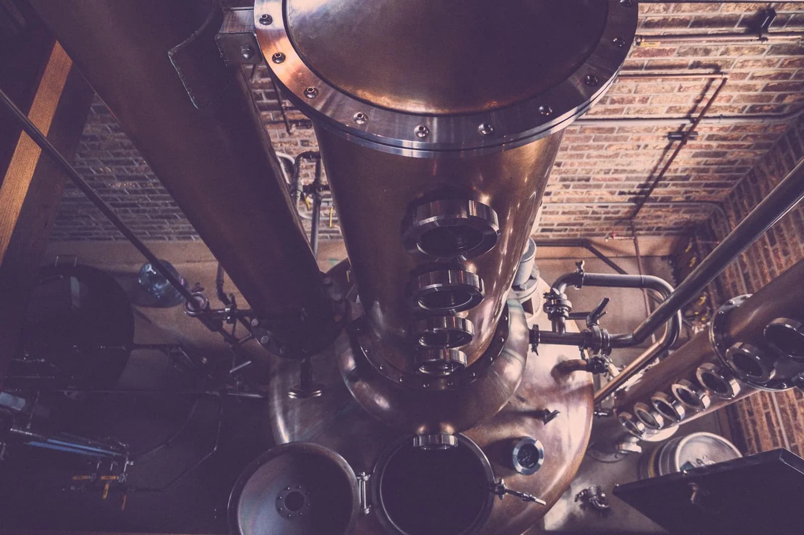 Colonne de distillation en cuivre avec hublots, vue plongeante dans une distillerie