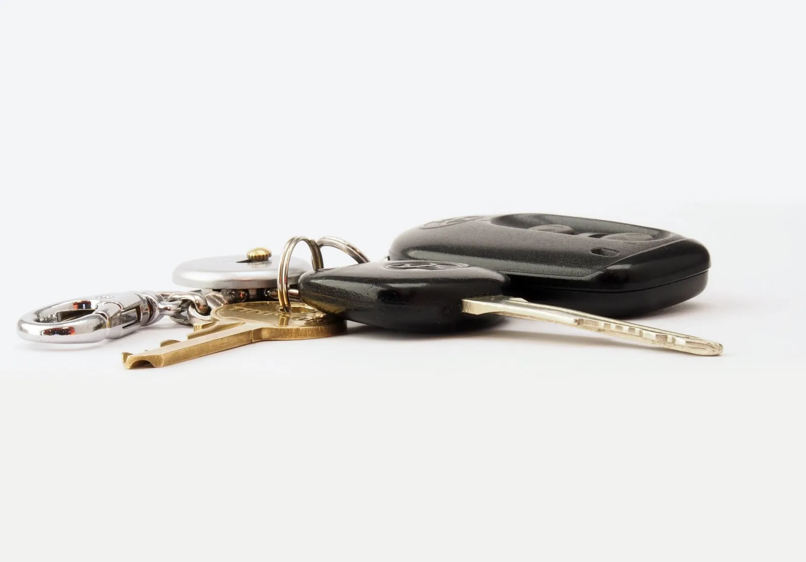 Clés de voiture avec télécommande posées sur un fond blanc