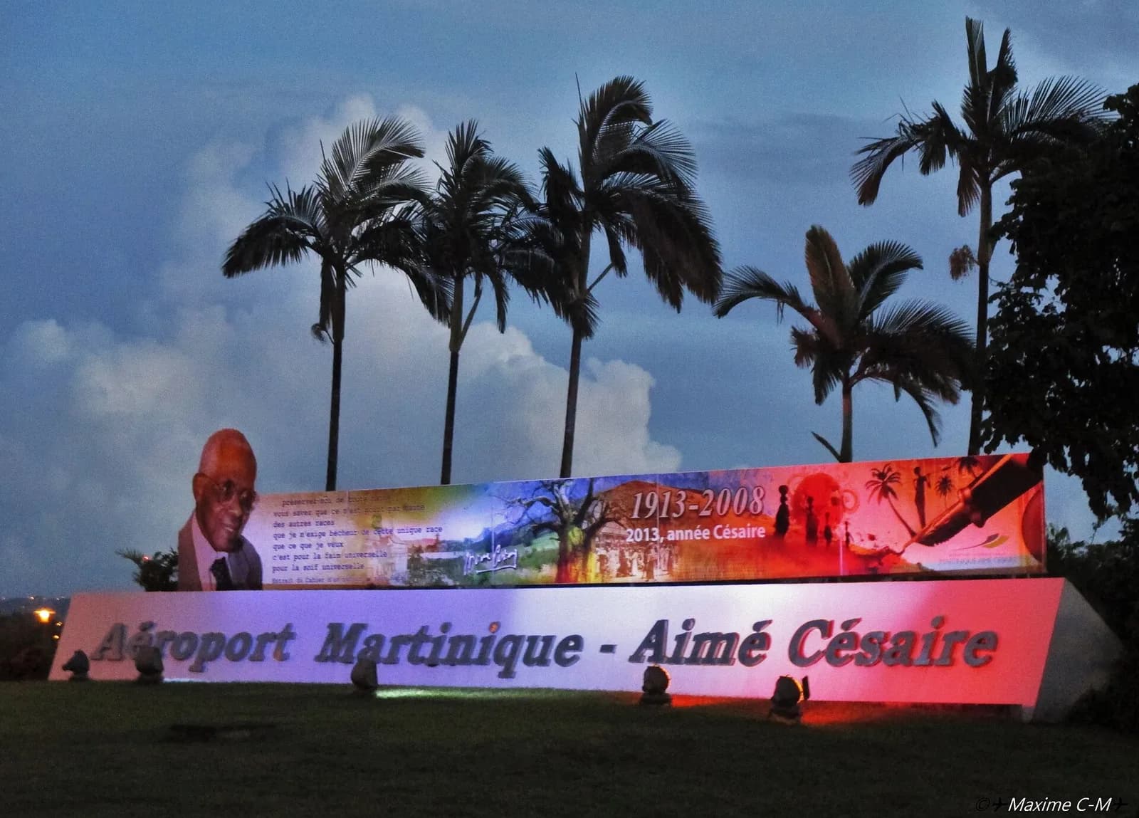 Panneau lumineux de l'aéroport Martinique - Aimé Césaire, au Lamentin, sous des palmiers au crépuscule