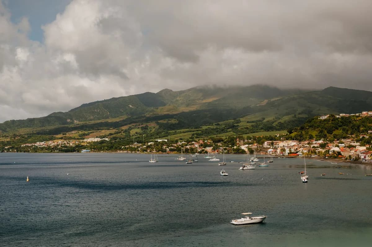 Baie et petite ville côtière au pied d'un massif volcanique dans les nuages, au nord de la Martinique