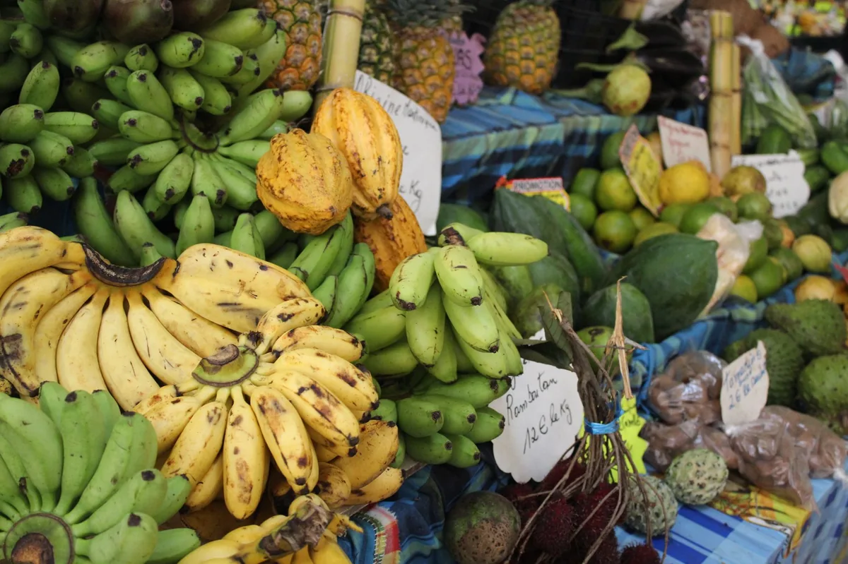 Étal de bananes, cacao, ramboutans et corossols sur un marché antillais