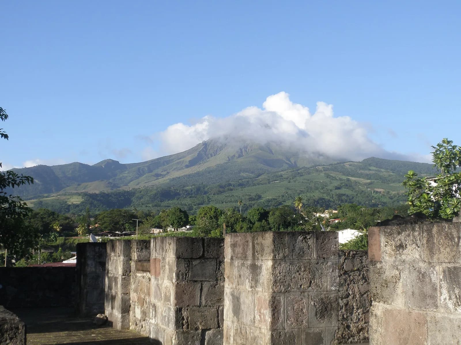 Vestiges du théâtre de Saint-Pierre avec la Montagne Pelée dans les nuages en arrière-plan