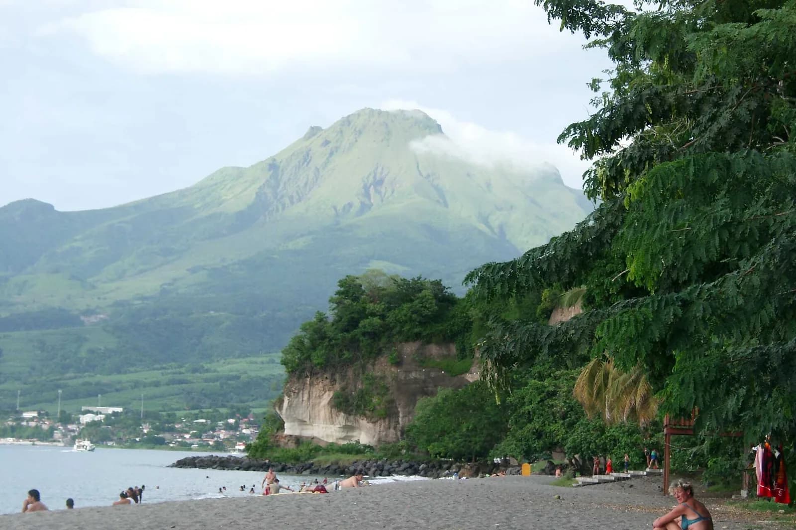 La Montagne Pelée, flanc couvert de végétation et sommet dans les nuages, vue depuis la plage du Carbet
