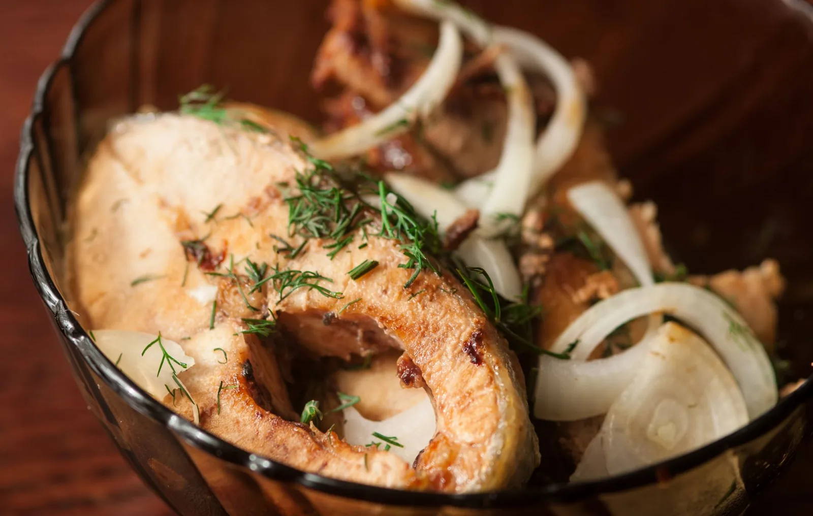 Tranche de poisson grillé dans un bol, avec oignons émincés et herbes ciselées