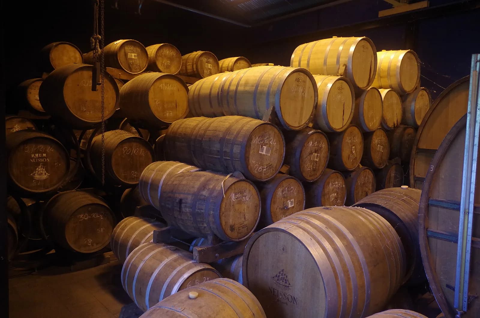 Fûts de vieillissement empilés dans le chai de la distillerie Neisson