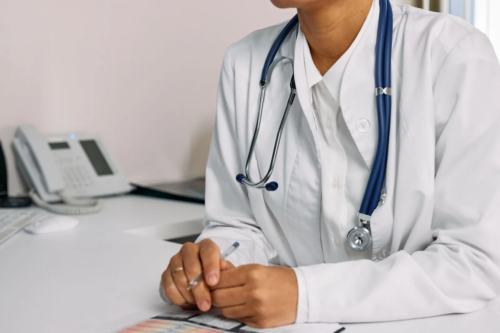 Médecin en blouse blanche avec un stéthoscope pendant une consultation à son bureau