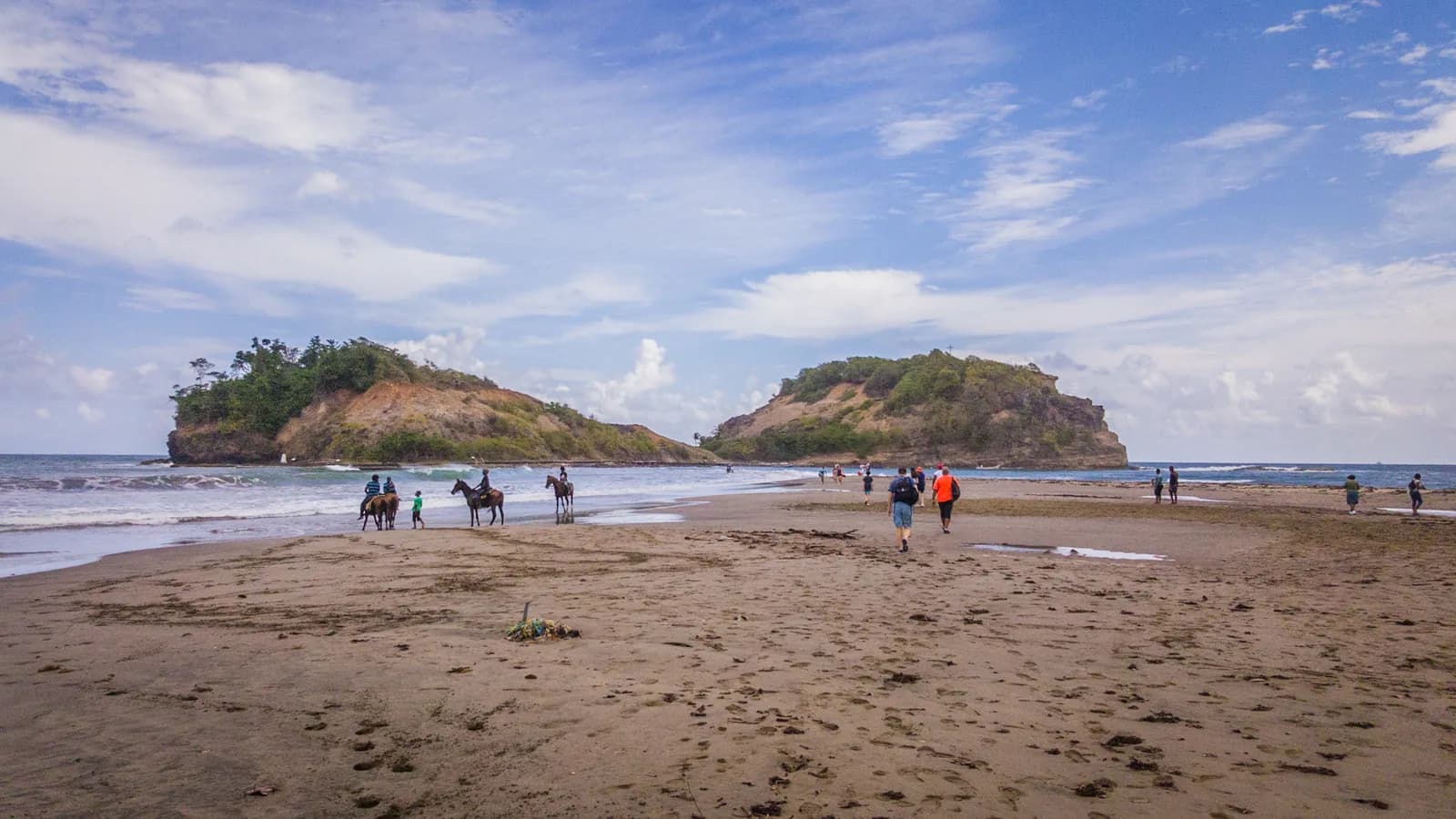 Marcheurs et cavaliers sur le banc de sable du tombolo de Sainte-Marie, en direction de l'îlet, en Martinique