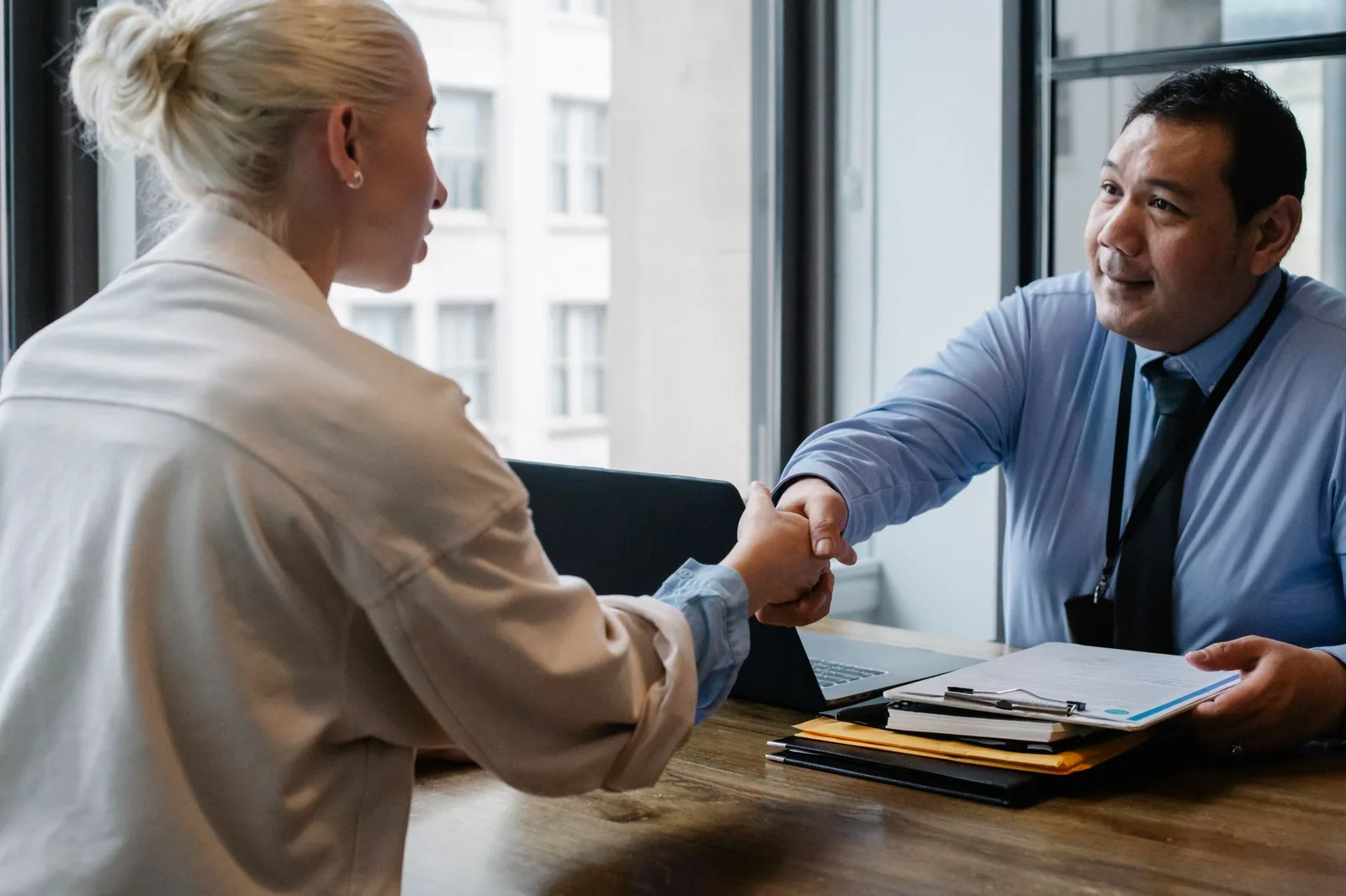 Poignée de main entre une candidate et un recruteur lors d'un entretien d'embauche dans un bureau