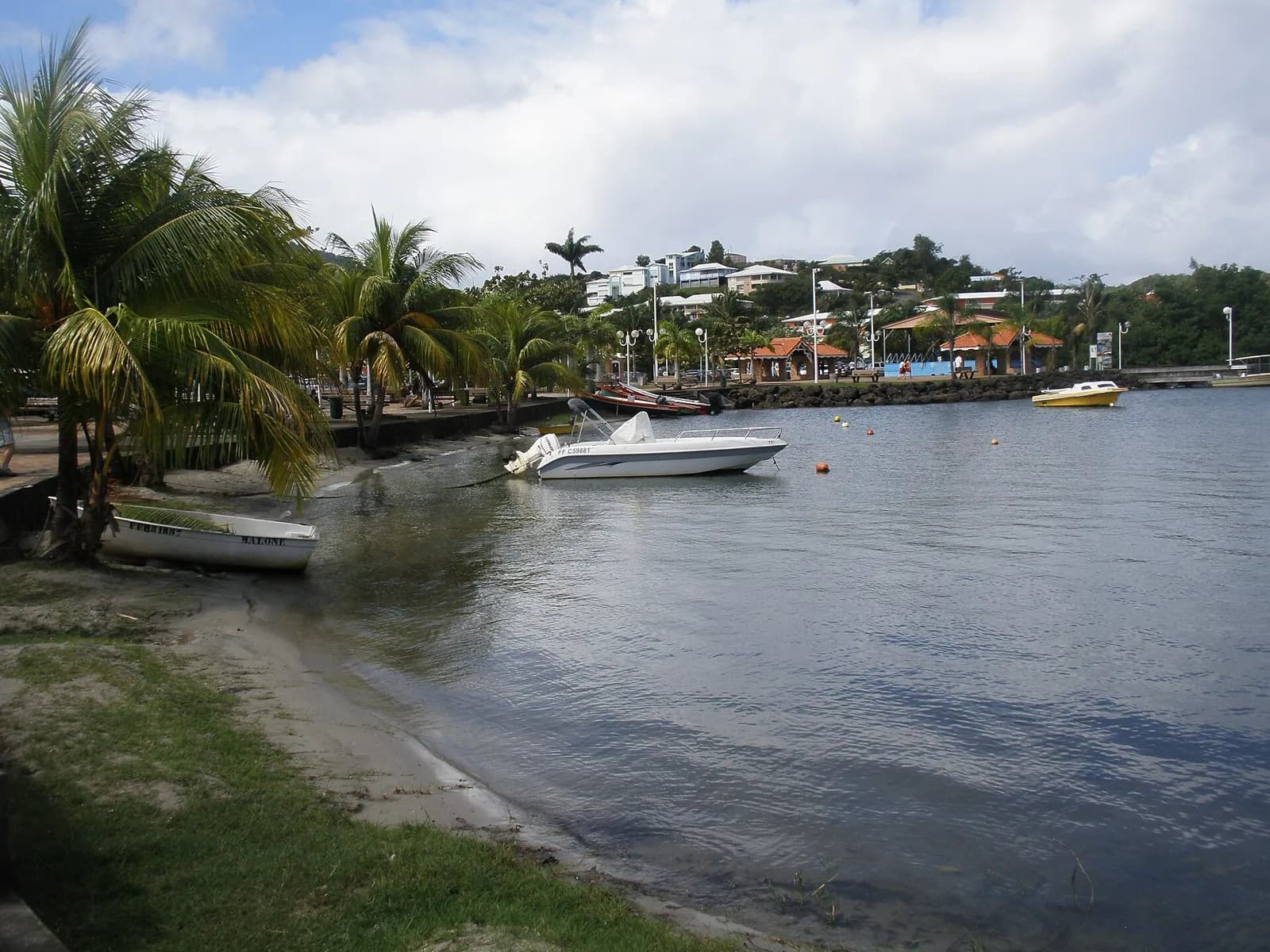 Front de mer des Trois-Îlets avec palmiers, barques et petites maisons sur la colline